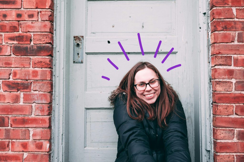 Blije jonge vrouw zittend voor een verweerde deur